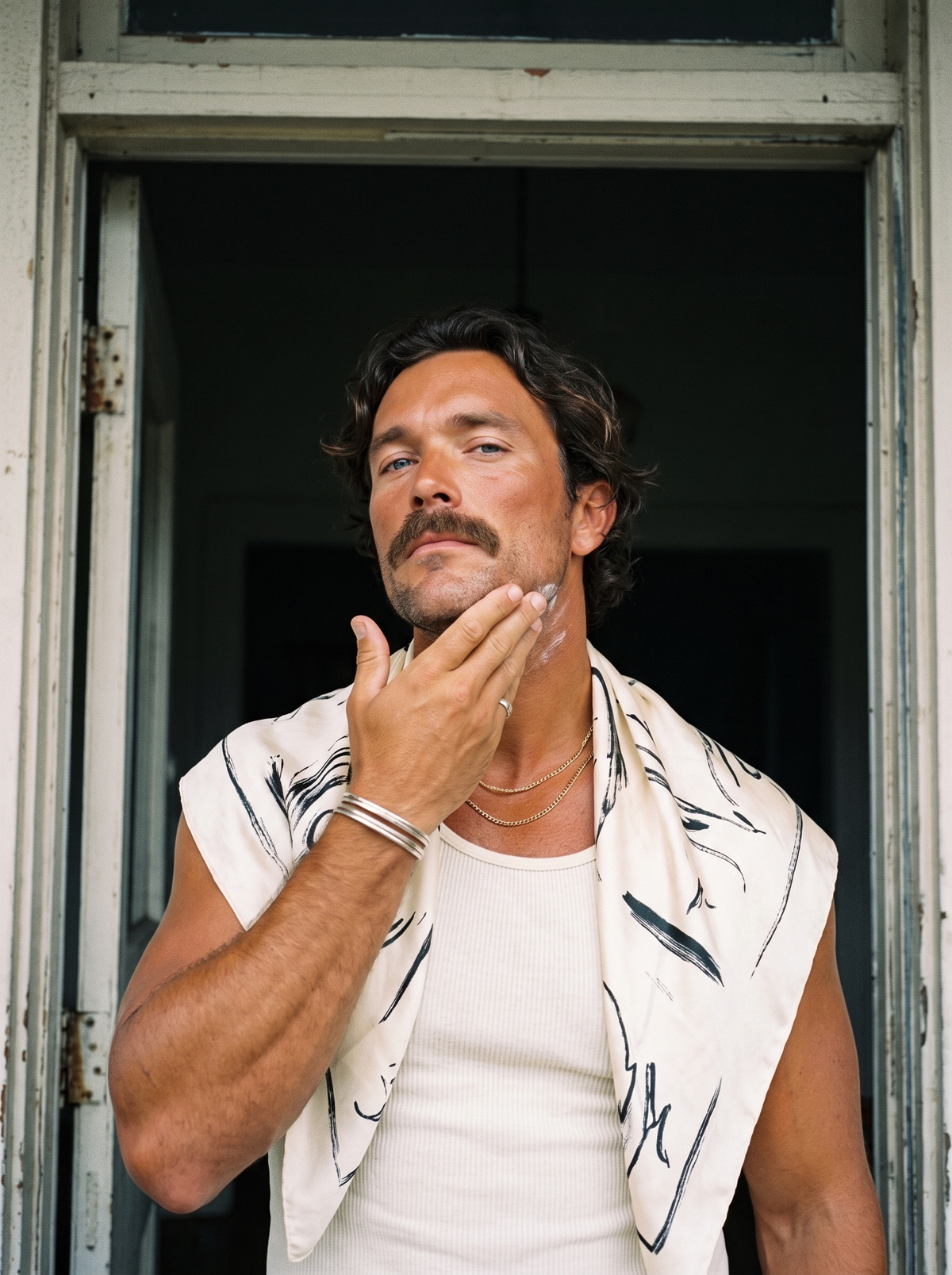 Man pressing tallow balm into his jawline in a doorway